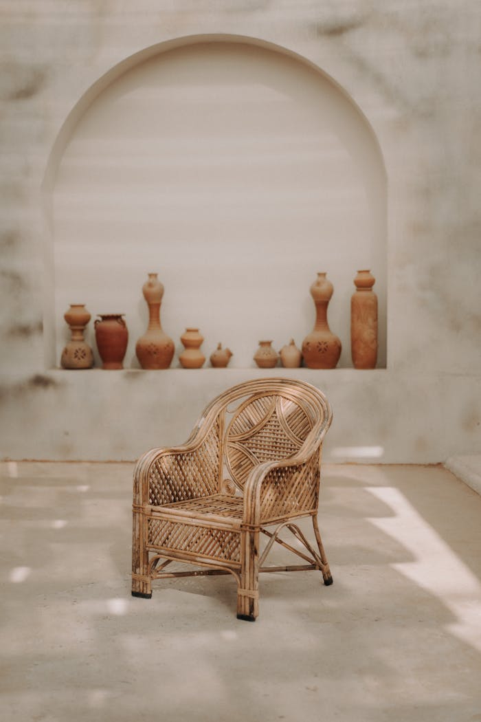 contact-img A stylish wicker armchair poses in a minimalist interior with clay vases and artistic decor.